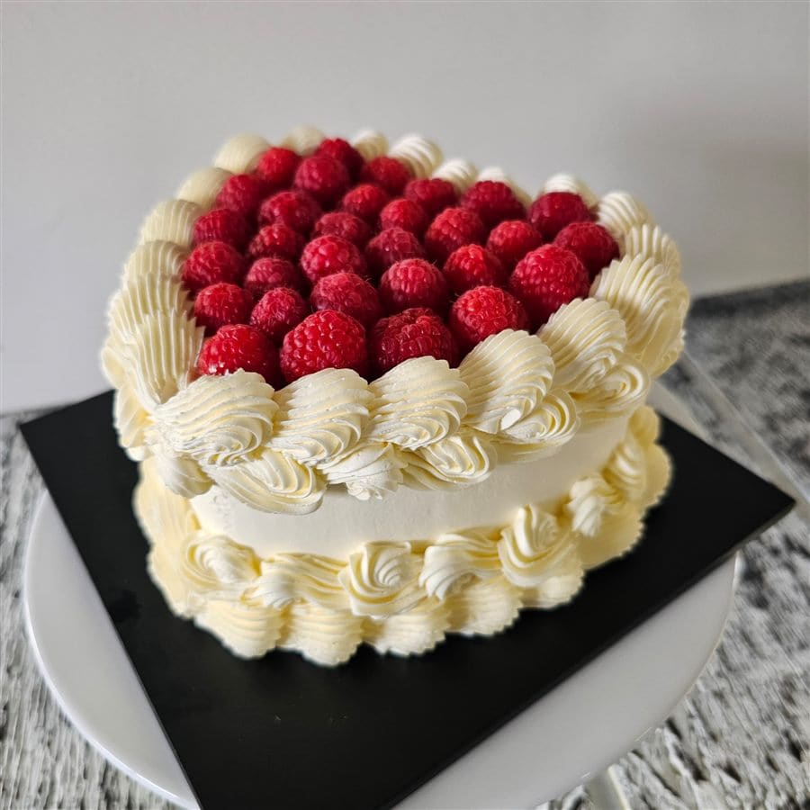 Heart-shaped raspberry birthday cake with piped cream by Amour Desserts